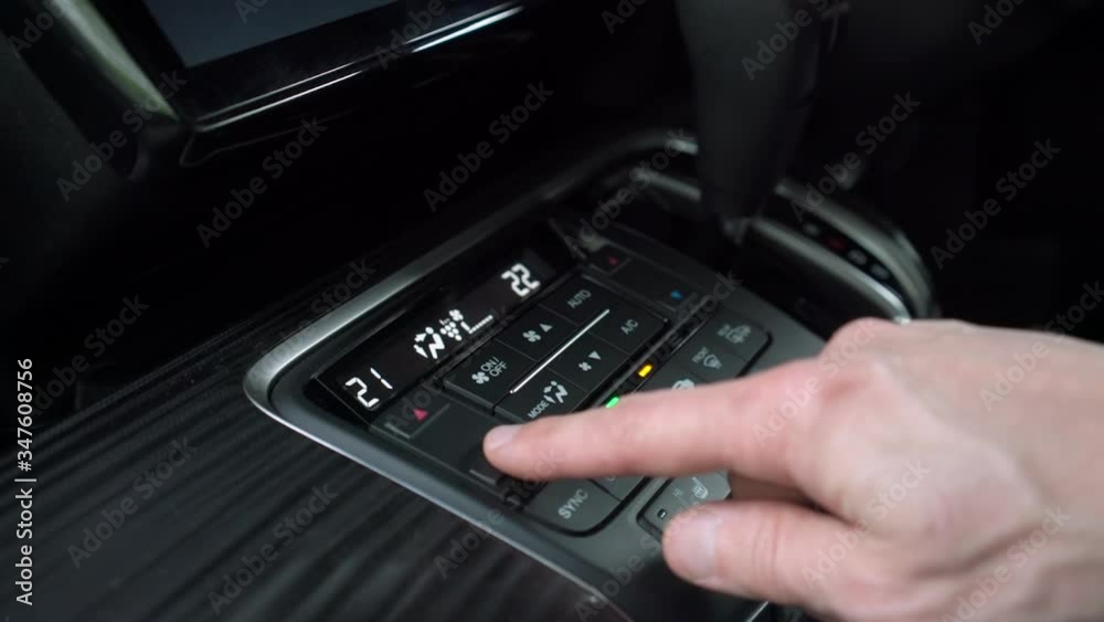 Man finger pushing buttons on сar сlimate сontrol system on car dashboard, adjusting the temperature inside the vehicle increases and reduces air, close up with selective focus Man finger pushing buttons on сar сlimate сontrol system on car dashboard, adjusting the temperature inside the vehicle increases and reduces air, close up with selective focus