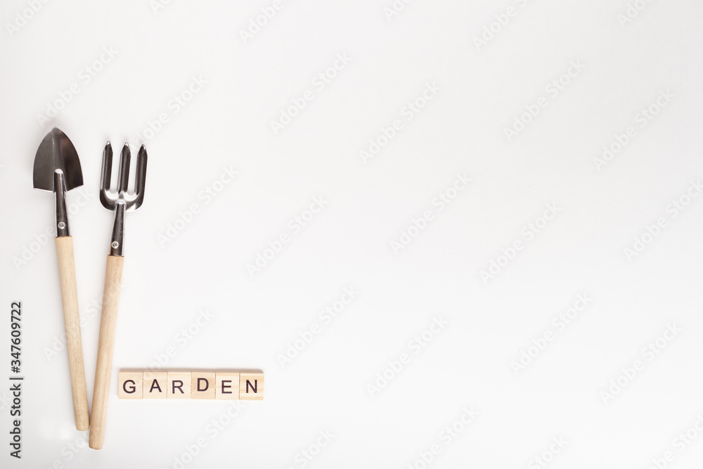 Tools for gardening at home. Copyspace for text, top view. Flatlay on white background. GARDEN text made of wooden cube. Tools for gardening at home. Copyspace for text, top view. Flatlay on white background. GARDEN text made of wooden cube.