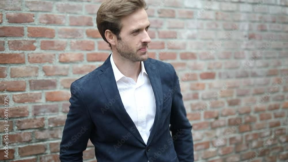handsome businessman touching his chin, standing with hands in pocket, pulling out his phone from his jacket, talking on the phone and gesturing outdoor handsome businessman touching his chin, standing with hands in pocket, pulling out his phone from his jacket, talking on the phone and gesturing outdoor