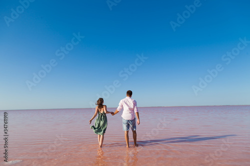 Fototapeta Naklejka Na Ścianę i Meble -  woman and man stand together in rose water lake against the blue sky