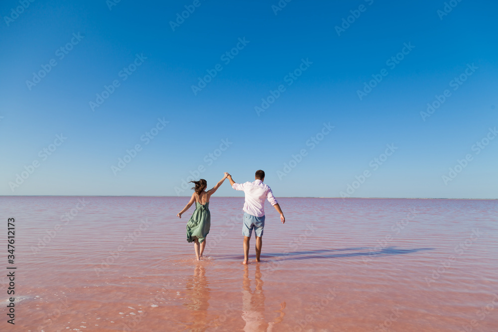 woman and man stand together in rose water lake against the blue sky