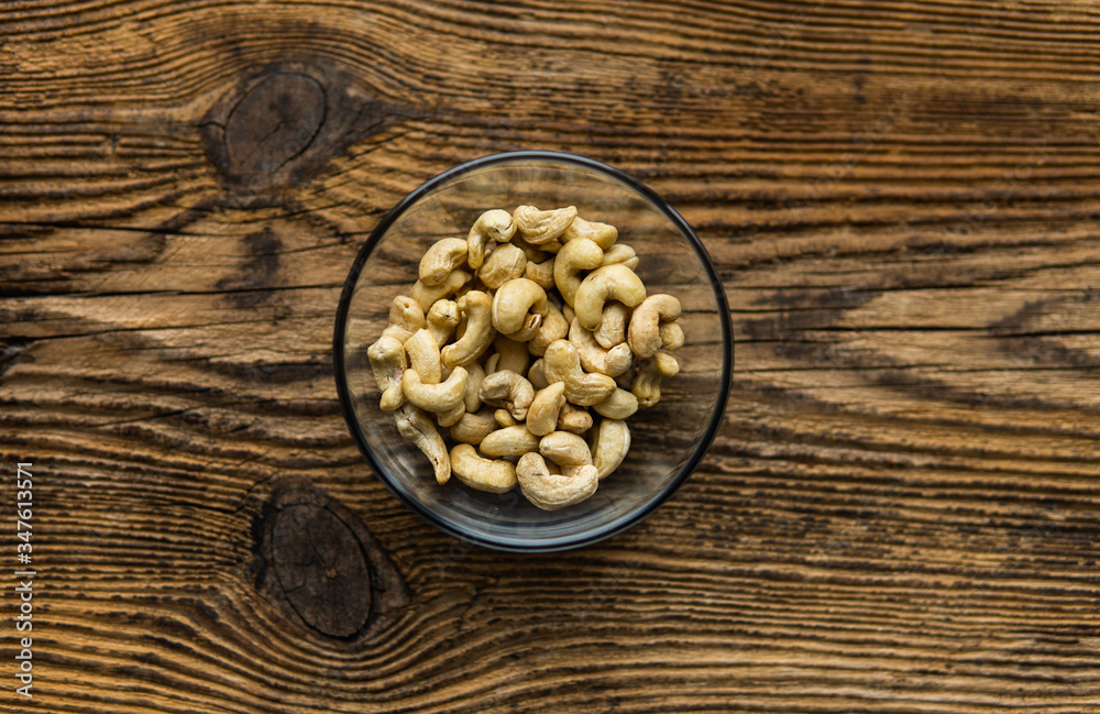 Cashew nuts in a small plate on a vintage wooden table as a background. Cashew nut is a healthy vegetarian protein nutritious food. Cashew nuts in a small plate on a vintage wooden table as a background. Cashew nut is a healthy vegetarian protein nutritious food.