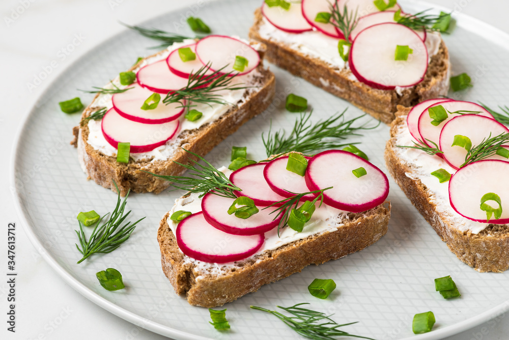 Healthy spring toasts with radish, curd cheese onion and dill in a plate on white marble table for healthy diet breakfast Healthy spring toasts with radish, curd cheese onion and dill in a plate on white marble table for healthy diet breakfast