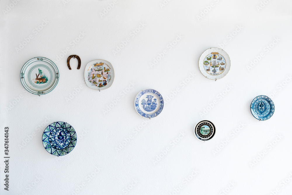White wall of a Mallorcan house decorated with beautiful vintage dishes. Spanish culture White wall of a Mallorcan house decorated with beautiful vintage dishes. Spanish culture