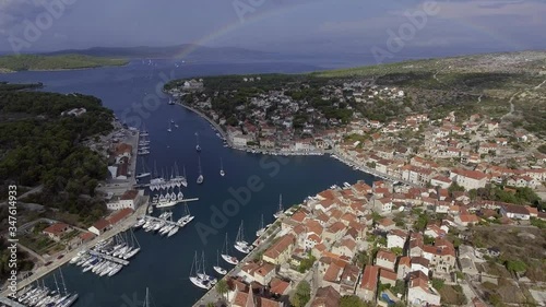 Aerial view of port in Milna, Croatia, drone view point, a full rainbow on the horizon, islands, is parked yachts, fishing boats, lodges with red roofs photo