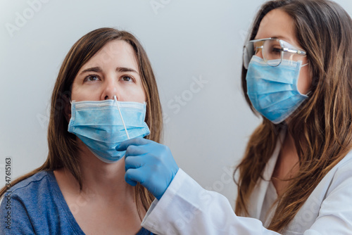 A doctor in a protective suit taking a nasal swab from a person to test for possible coronavirus infection. Nasal mucus testing for viral infections.