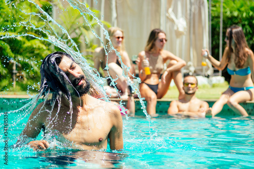 indian handsome long wet haired man in pink sunglasses , happy friends background chill out mood