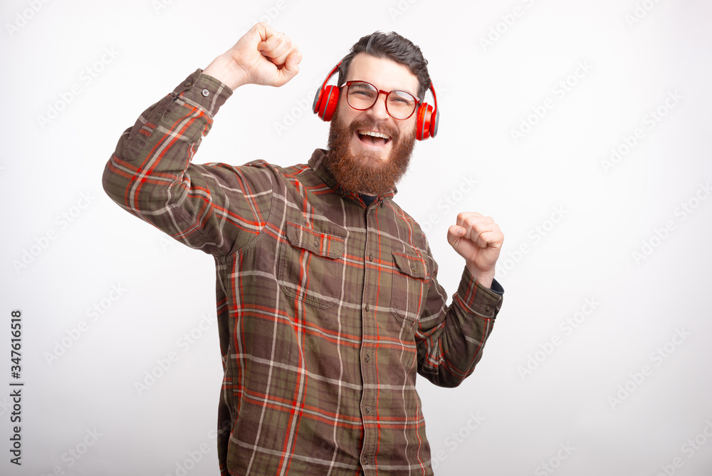 Fototapeta premium Happy bearded man wearing headphones is dancing over white background.