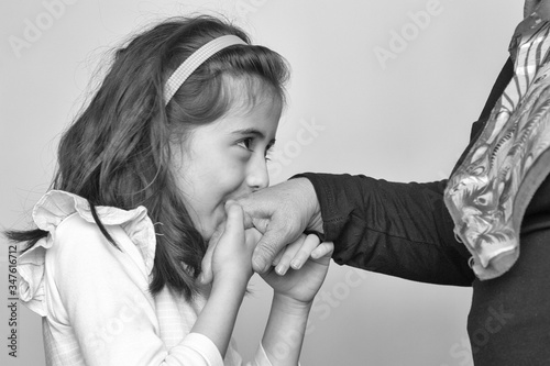 Little baby girl kiss her grandmother's hand during Eid mubarak (Turkish Ramazan or Seker Bayram). Adorable child kiss elderly woman hand to show respect. Cute girl follow muslim Ramadan traditions