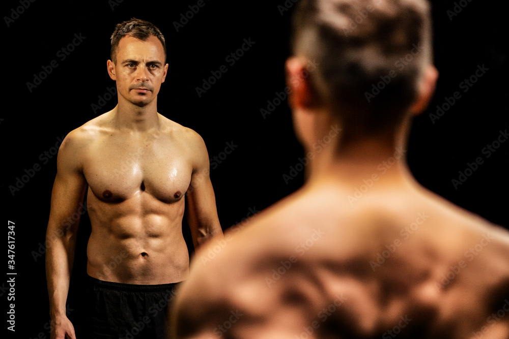 Fototapeta premium Shirtless fit young man working out in dark fitness studio