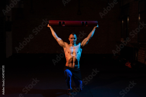 Shirtless fit young man working out in dark fitness studio © Marcel Poncu