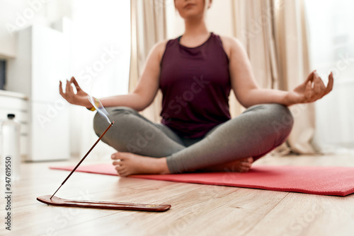 Revive your spirit. Cropped shot of young curvy woman in sportswear burning incense while sitting in the lotus position on a yoga mat at home