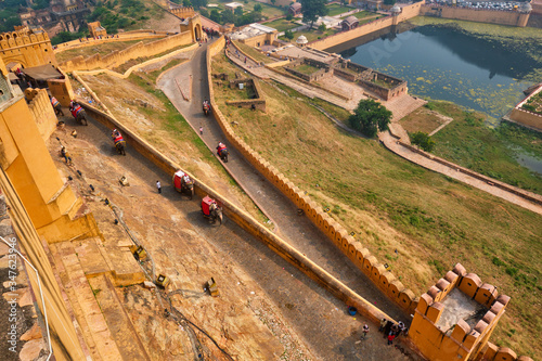 Tourists riding elephants on ascend to Amer (Amber) fort, Rajasthan, India. Amer fort is famous tourist destination and landmark