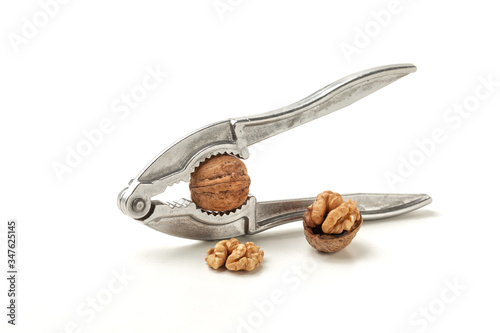 nutcracker with closed and cracked walnuts on white background