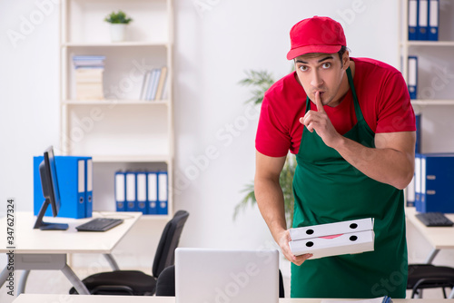Young male pizza courier in industrial espionage concept
