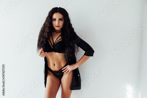 portrait of a beautiful fashionable woman in black lingerie in a white room
