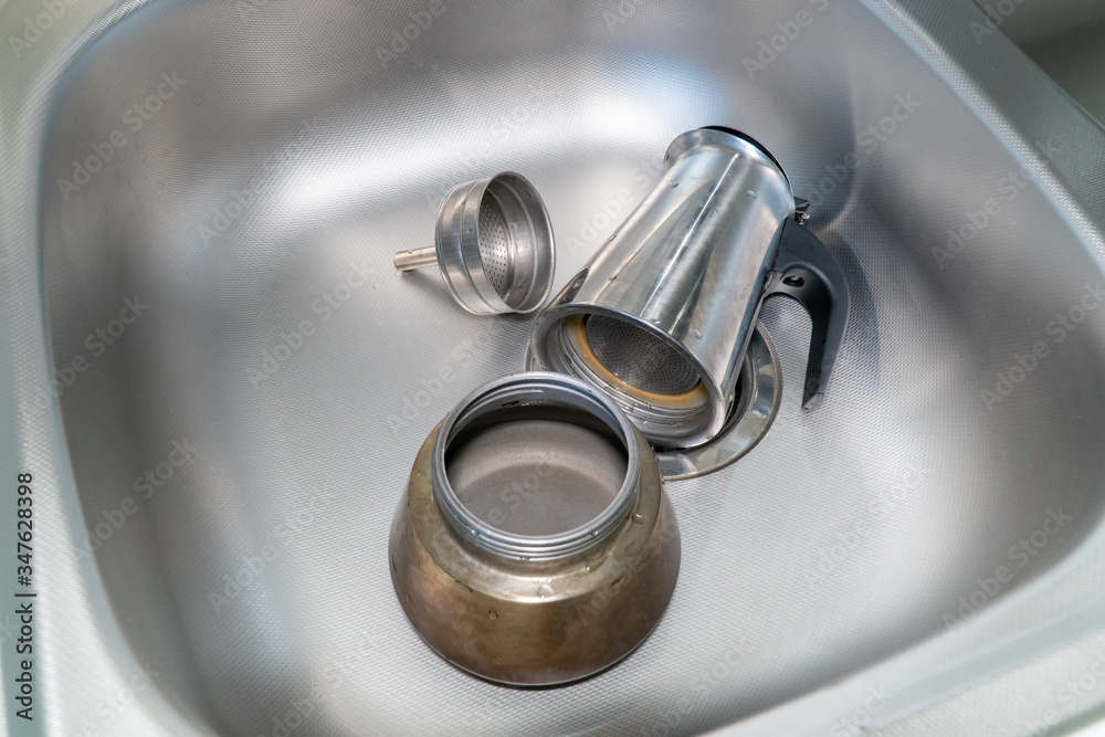 Coffee maker on the stove. Italian espresso coffee maker or Moka pot disassembled in the sink. Disassembled coffee maker in the sink