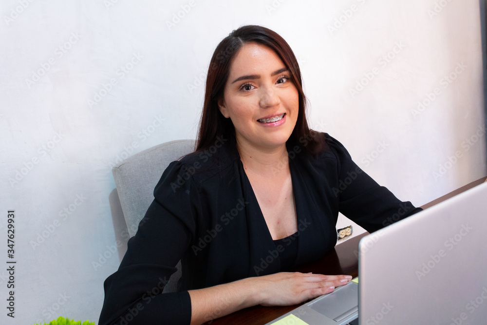 Young Hispanic woman in black clothes doing home office with a white laptop, smiling and happy to work from home Young Hispanic woman in black clothes doing home office with a white laptop, smiling and happy to work from home