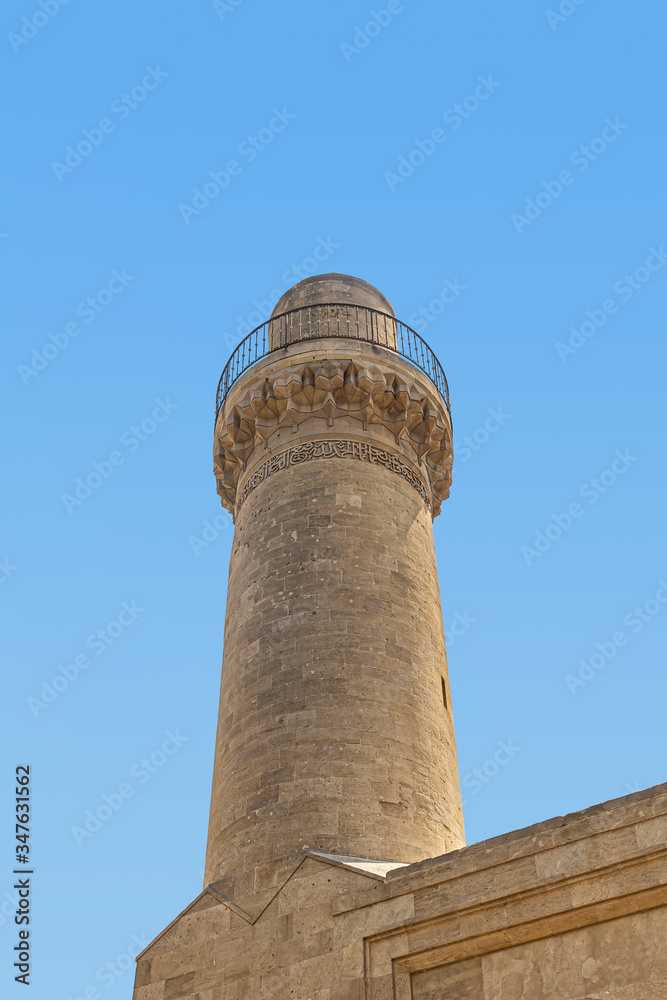 Minaret in the Palace of Shirvanshahs against the blue sky, in the historical district of Baku