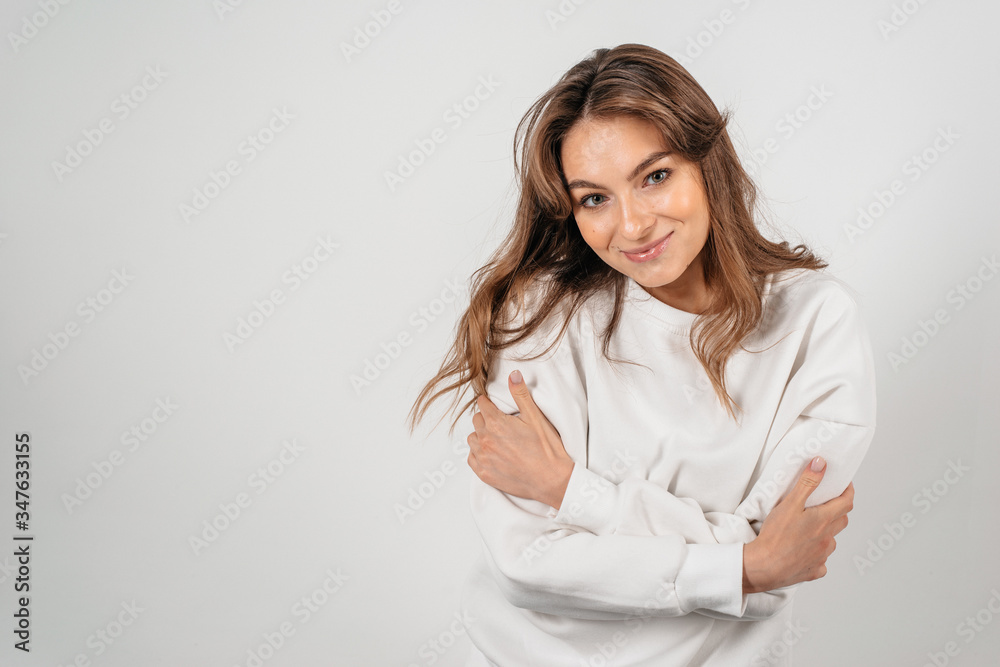 Young beautiful woman standing on the white background hugging herself with hands Young beautiful woman standing on the white background hugging herself with hands