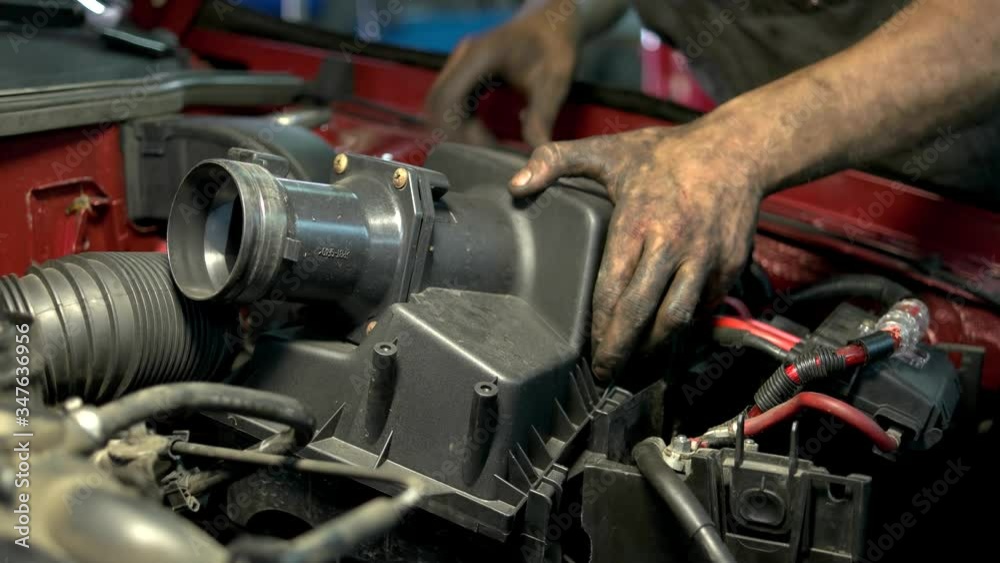 Mechanic worker is installing car engine detail. Car service worker installing car part. Mechanic worker is installing car engine detail. Car service worker installing car part.