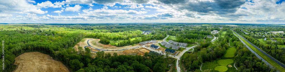 Aerial panorama of large construction site of a new single family home and town house neighborhood in the middle of a golf course in Turf Valley Maryland with home sites and triplexes