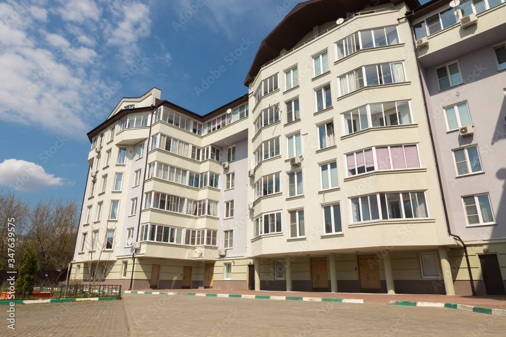 Modern apartment building is on a background of blue sky at sunny day. The concept of comfortable house in the city.