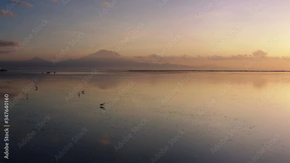 Local fishing boat cruising on still ocean water in Bali Indonesia with the volcano Agung sitting in thoe horizon Local fishing boat cruising on still ocean water in Bali Indonesia with the volcano Agung sitting in thoe horizon