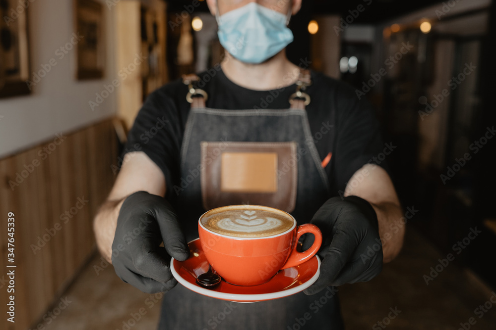 barista camarero con mascarilla y guantes está enseñando una taza roja de café con dibujo latte art barista camarero con mascarilla y guantes está enseñando una taza roja de café con dibujo latte art