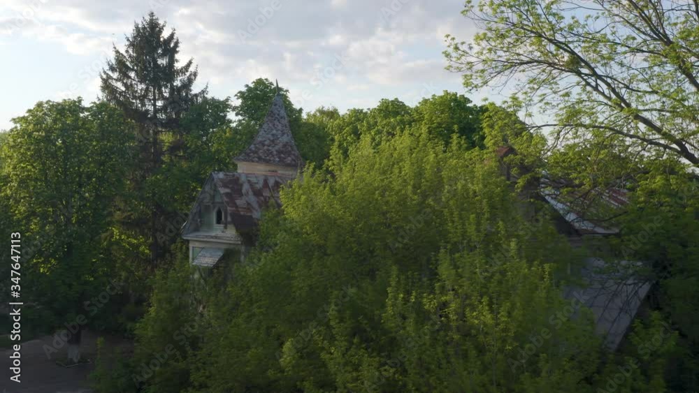 Abandoned 19th-century Victorian house in a dense spring forest. Aerial low angle view. Abandoned 19th-century Victorian house in a dense spring forest. Aerial low angle view.