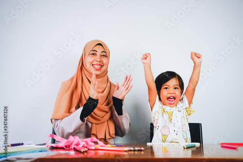 Young musilm woman with her cute daughter playing and learning at home. Motherhood having good time. photo