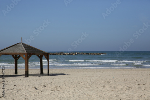 wooden gazebo or canopy on a white sand beach against a blue sky and blue sea on a tropical resort. Concept of tourism and leisure and vacation