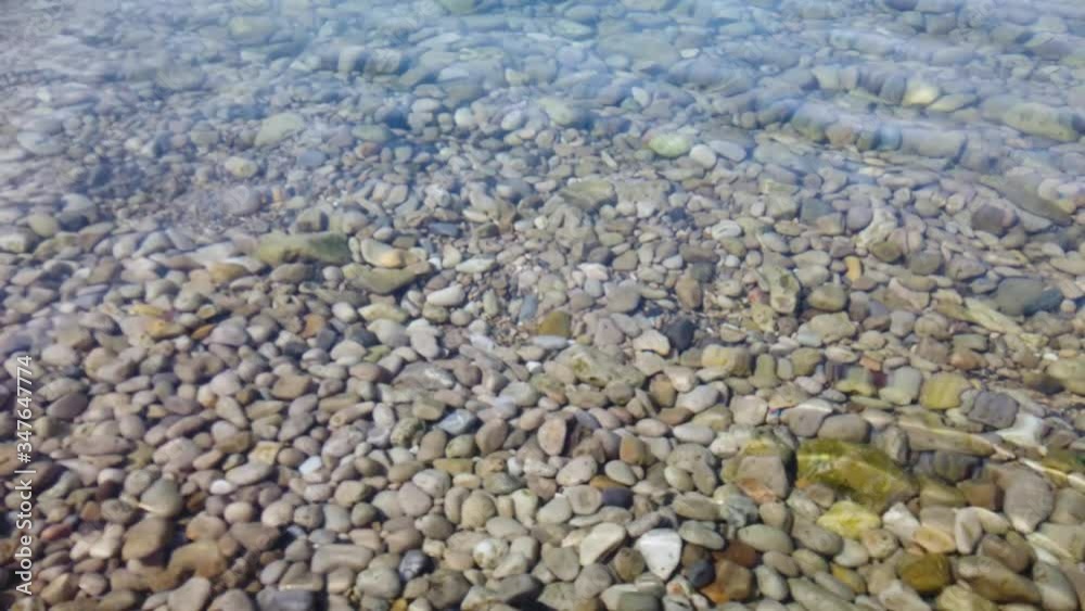 Static shot of stones under clear water surface as small waves come in Static shot of stones under clear water surface as small waves come in