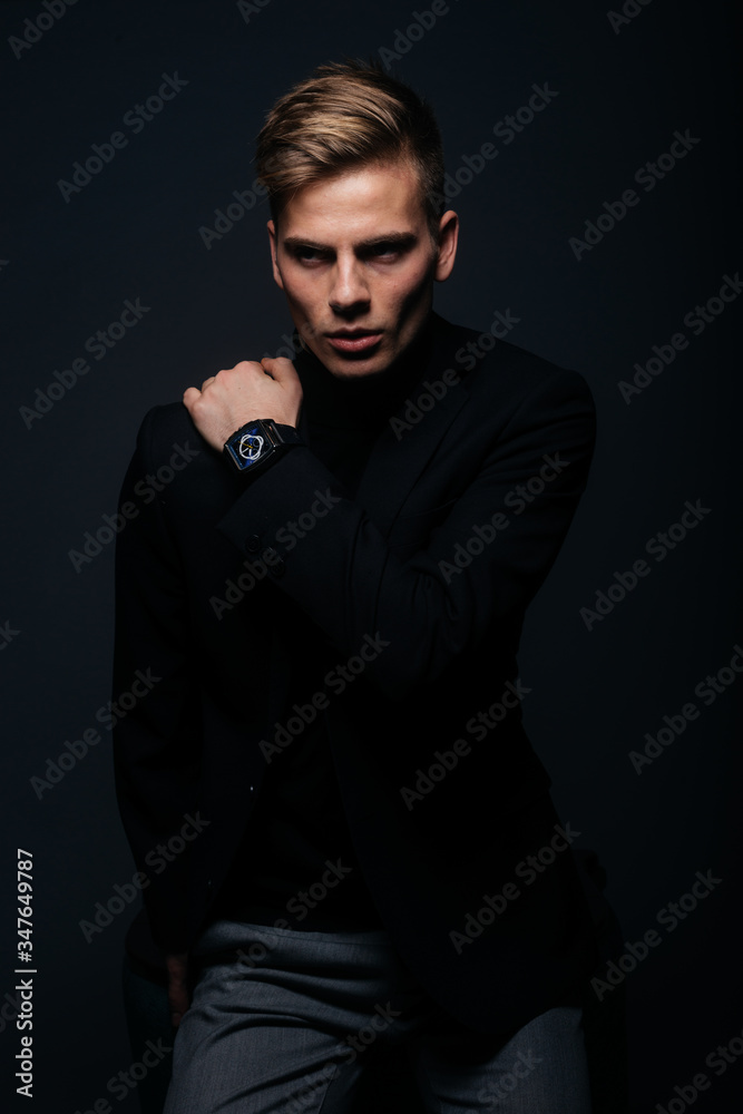 Fototapeta premium Formally dressed man with sharp jawline in his 20's posing in a studio in front of a black background.