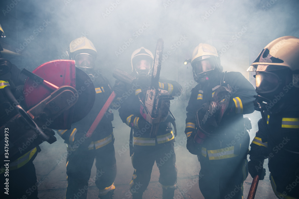 Group of firemen with gas masks standing in the middle of the chainsaw's smoke Group of firemen with gas masks standing in the middle of the chainsaw's smoke