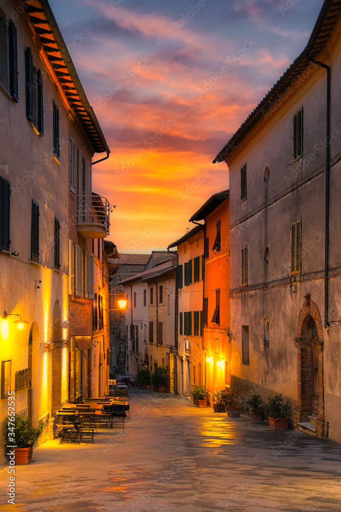 020-05-10 A STREET IN A SMALL TOWN IN THE TUSCANY REGION AS DUSK SETTLES IN WITH A BRIGHT ORANGE SKY