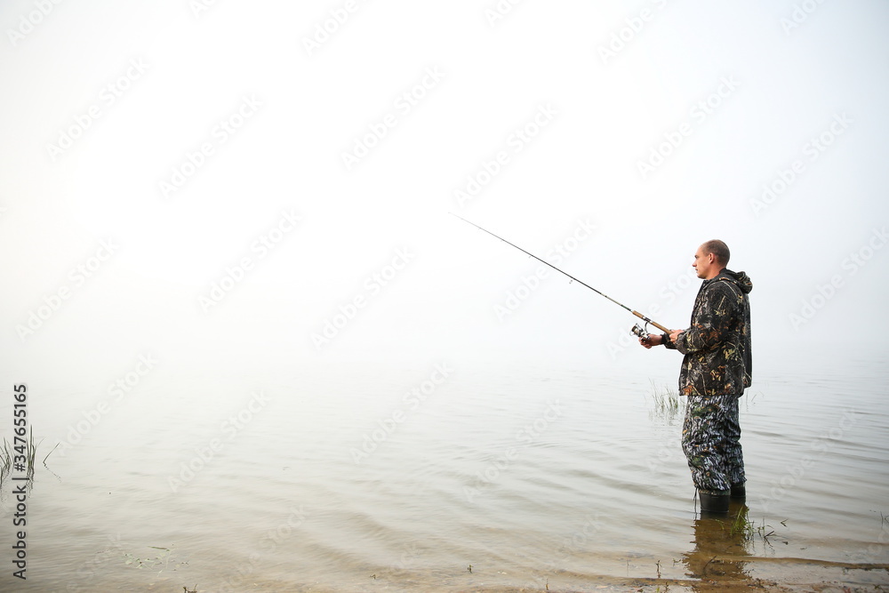 fisherman holding fishing rod on the lake in fog fisherman holding fishing rod on the lake in fog