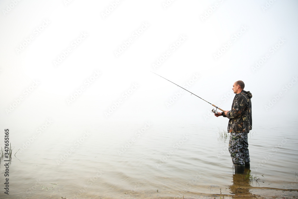 fisherman holding fishing rod on the lake in fog