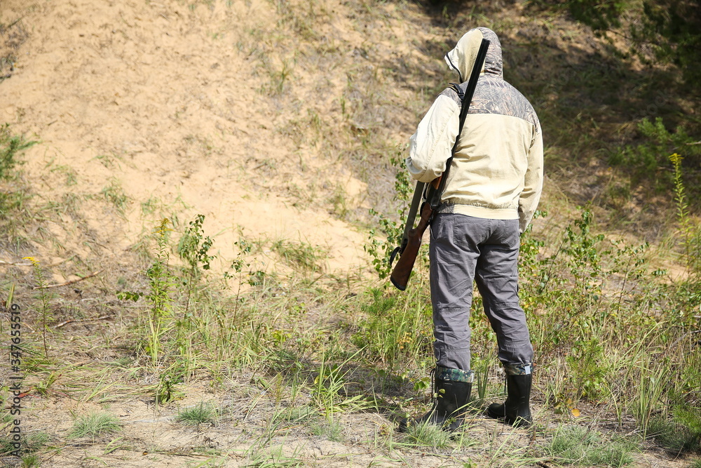 standing hunter with rifle in summer forest standing hunter with rifle in summer forest
