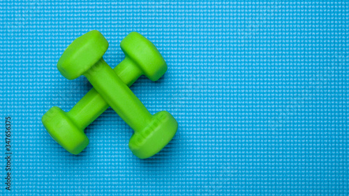 two green dummbells on blue exercise mat