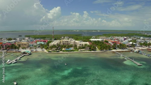 Aerial view of hotel near sea in city against sky on sunny day, swimming pool amidst residential buildings while drone moving backward - Great Blue Hole, Belize photo