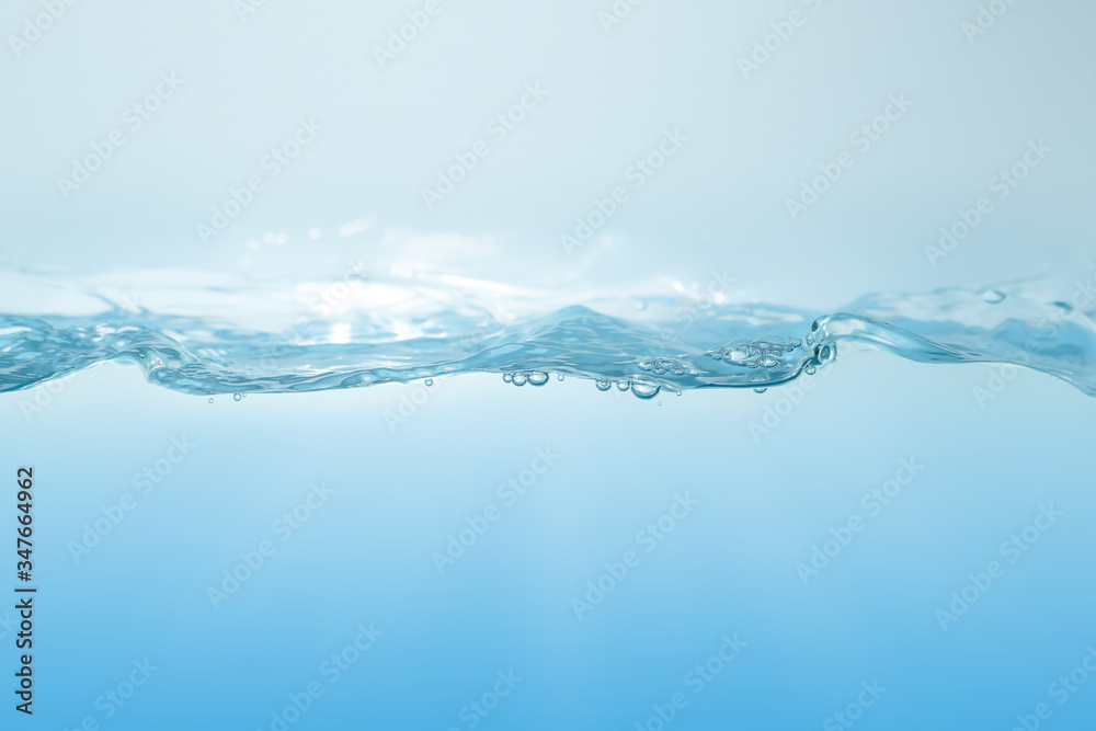 Water splash on blue background. Aqua flowing in waves and creating bubbles. Drops on the water surface feel fresh and clean.