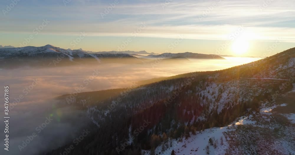 Aerial panning shot of clouds amidst snowcapped mountains against sky during sunrise - Falkert, Austria Aerial panning shot of clouds amidst snowcapped mountains against sky during sunrise - Falkert, Austria