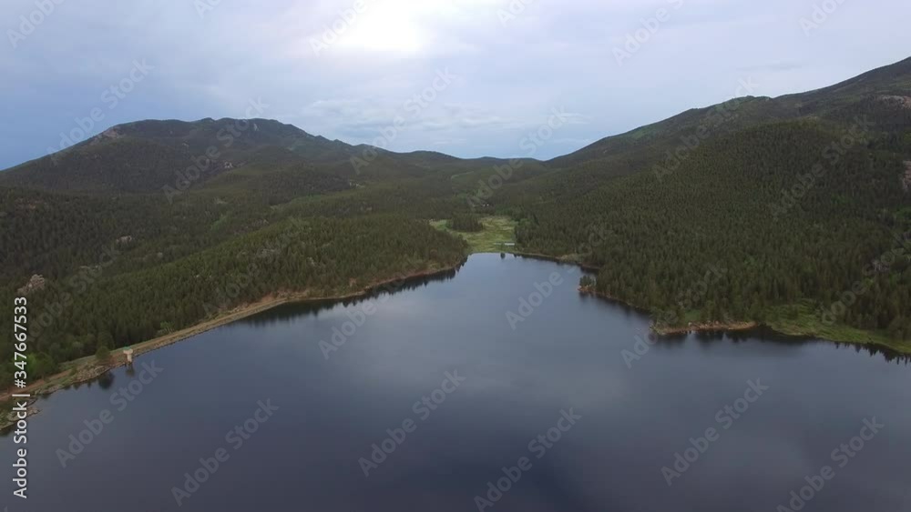 Aerial shot of beautiful calm lake amidst forest against sky, drone moving forward over idyllic mountains against sky - Lake Wellington, Colorado Aerial shot of beautiful calm lake amidst forest against sky, drone moving forward over idyllic mountains against sky - Lake Wellington, Colorado