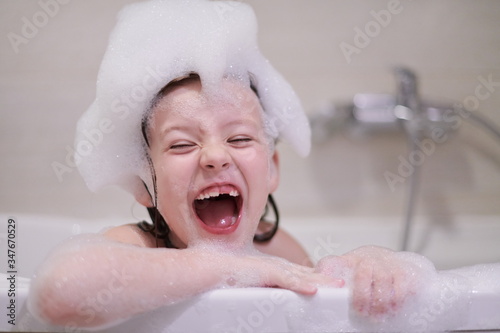 little girl in bath playing with soap foam
