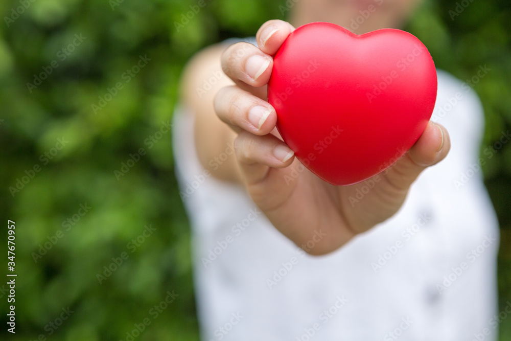 Selective focus of A woman with a heart shaped ball in her hand  on blurred background