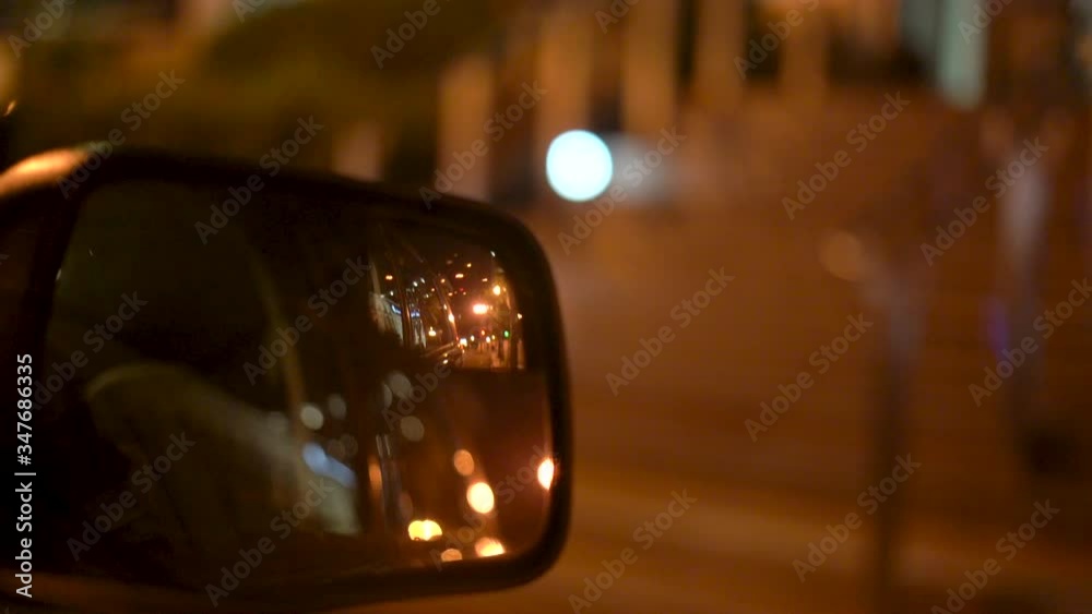 4K drone footage of side mirror on car at night.