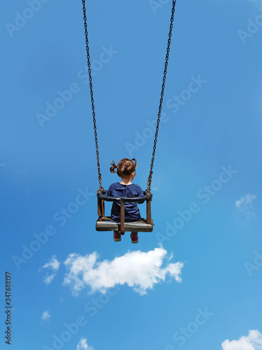 swing and child playing flying among clouds in the blue sky