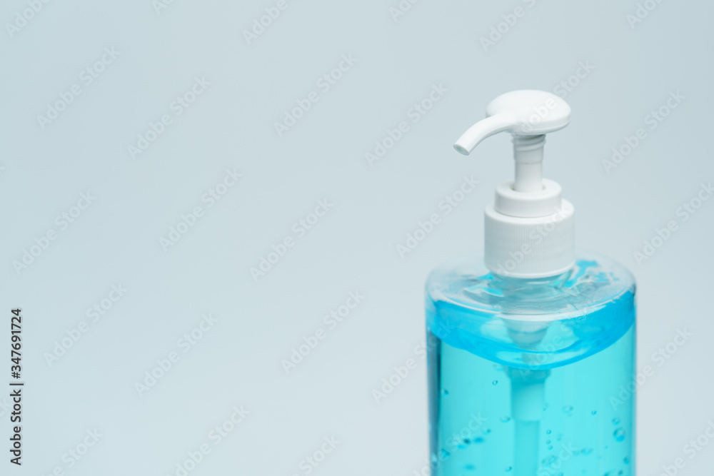 Clear blue hand sanitizer in a clear pump bottle on a white background. Clear blue hand sanitizer in a clear pump bottle on a white background.
