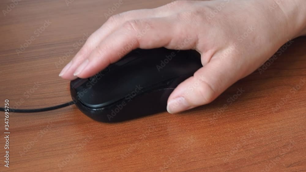 Close-up of a woman's hand holding a computer mouse. Work at the table with a computer mouse. Close-up of a woman's hand holding a computer mouse. Work at the table with a computer mouse.